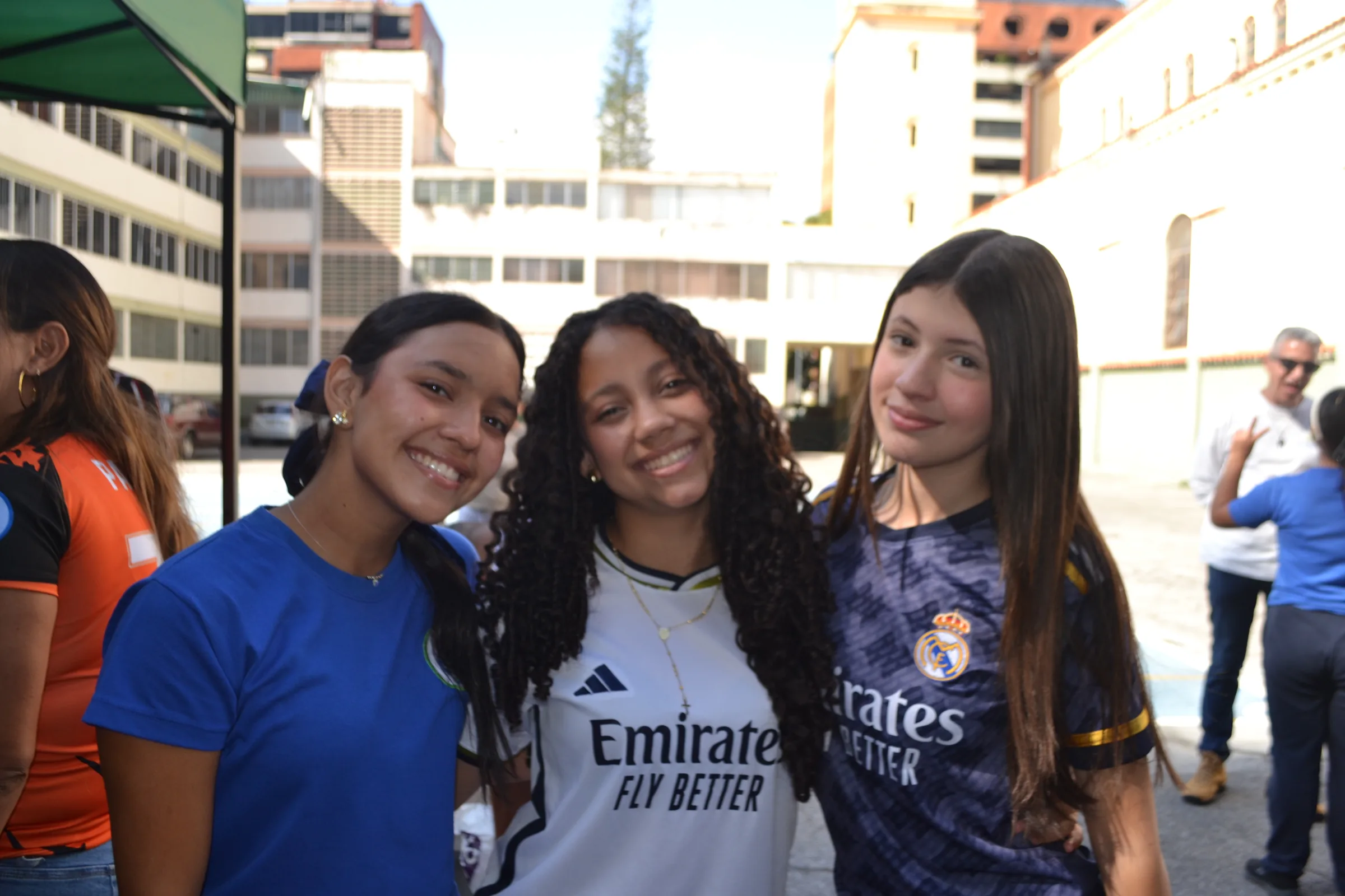 Tres estudiantes sonríen en el patio del colegio