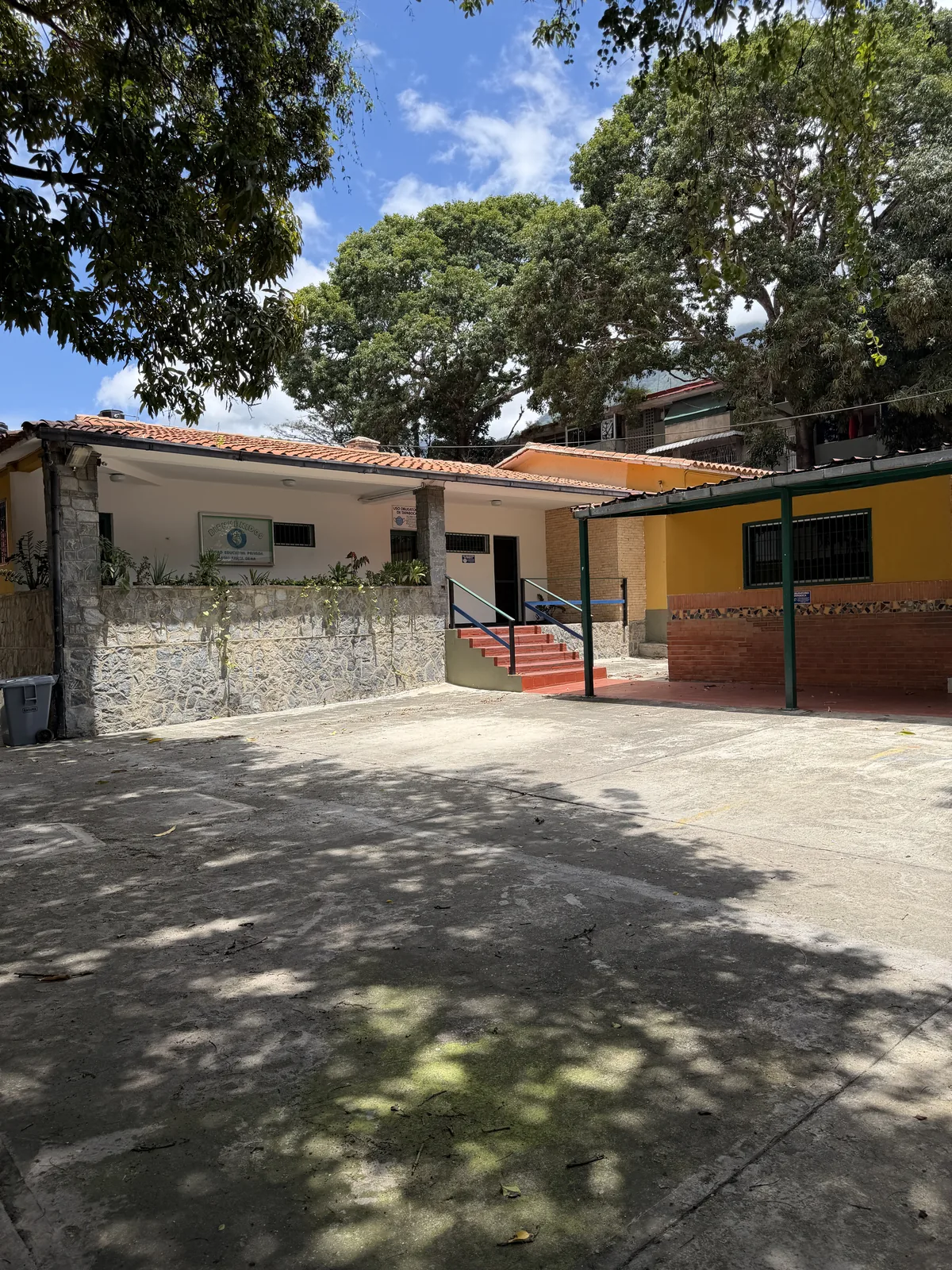 Patio sombreado por árboles dentro del colegio