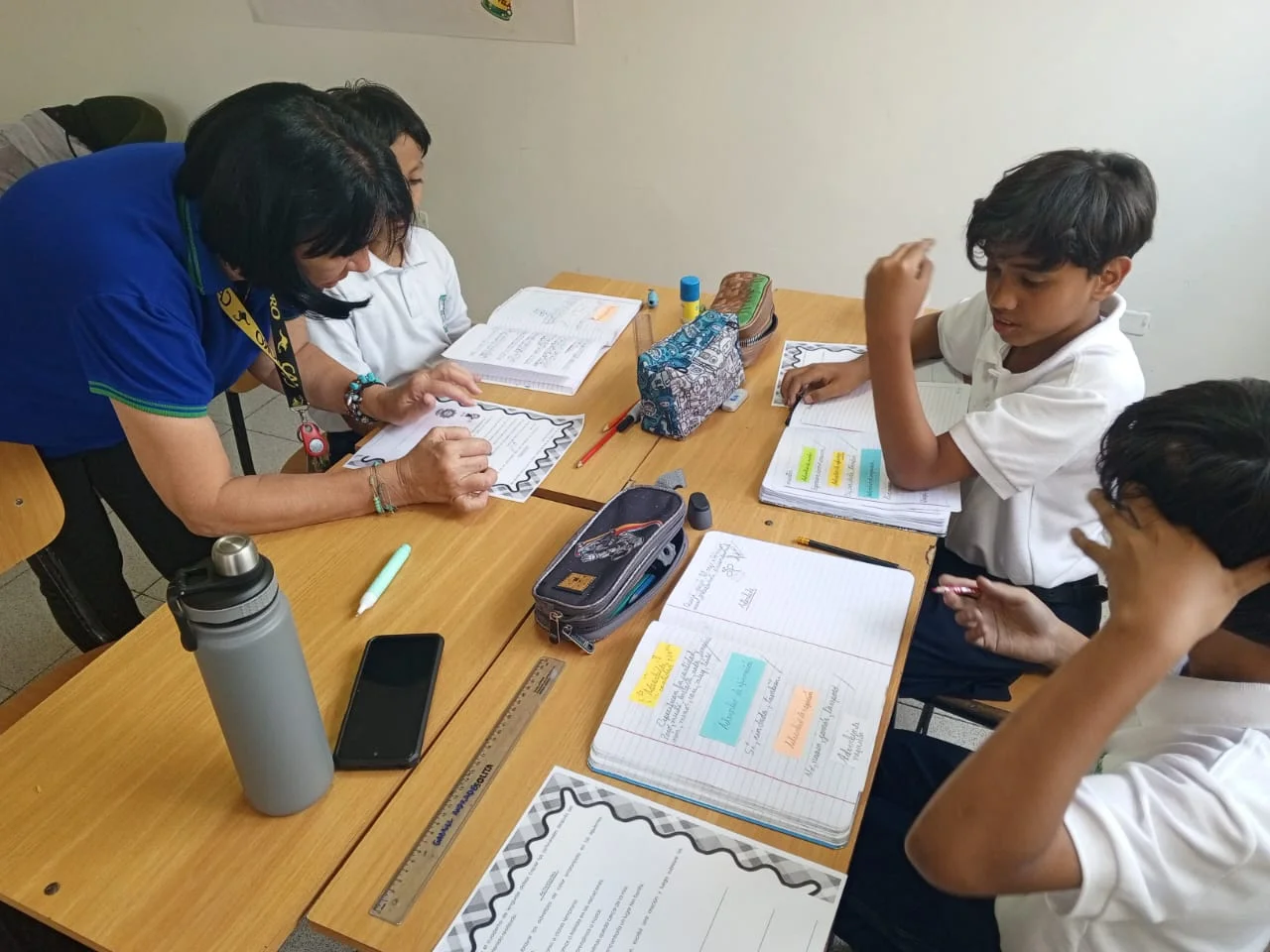 Docente acompaña a estudiantes durante una actividad en el aula