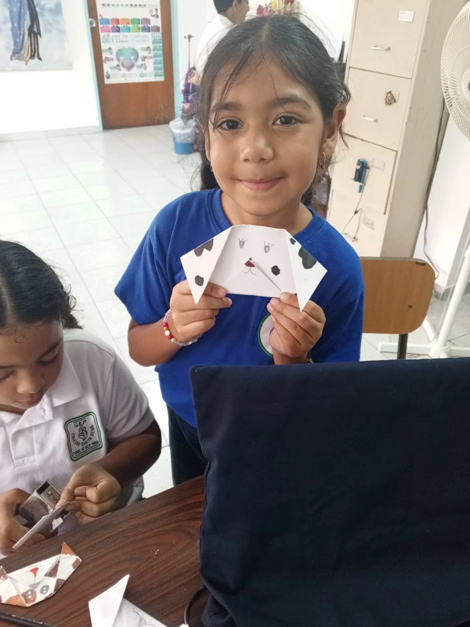 Estudiante muestra su trabajo creativo en el aula